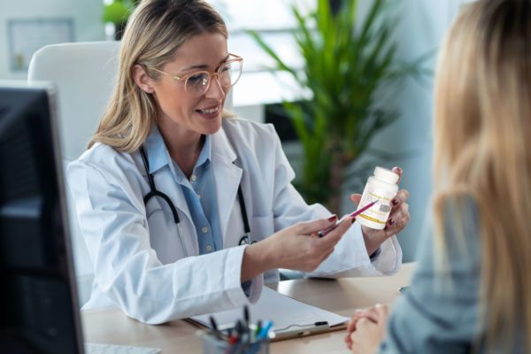 Woman presenting Biotics Research omega-3 product with the ORIVO logo